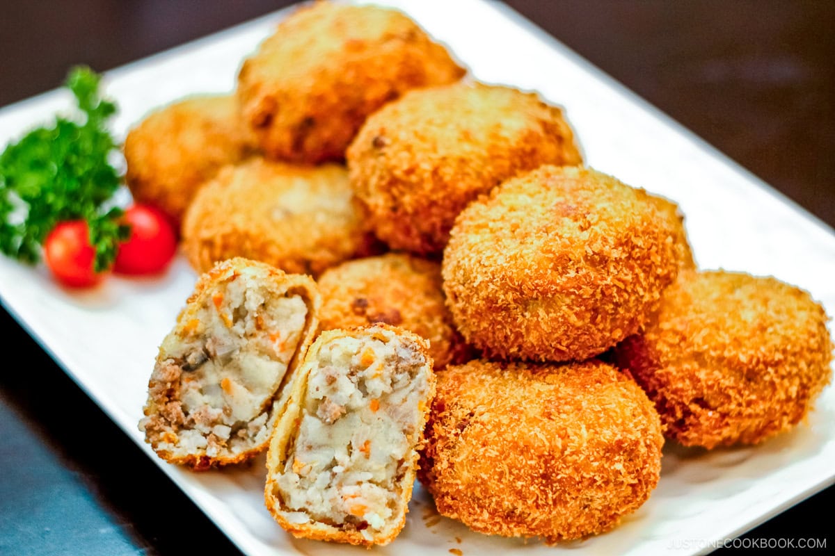 A white rectangular plate containg potato and meat croquettes.