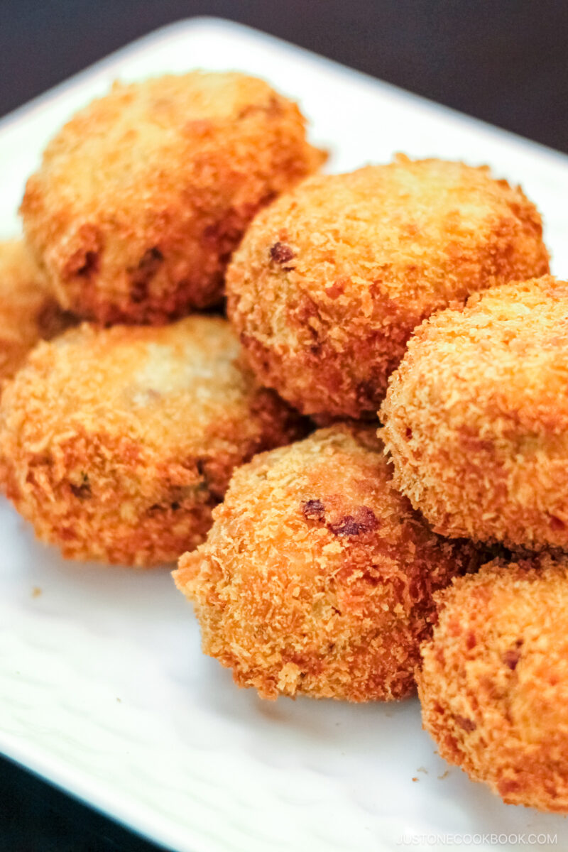 A white rectangular plate containg potato and meat croquettes.