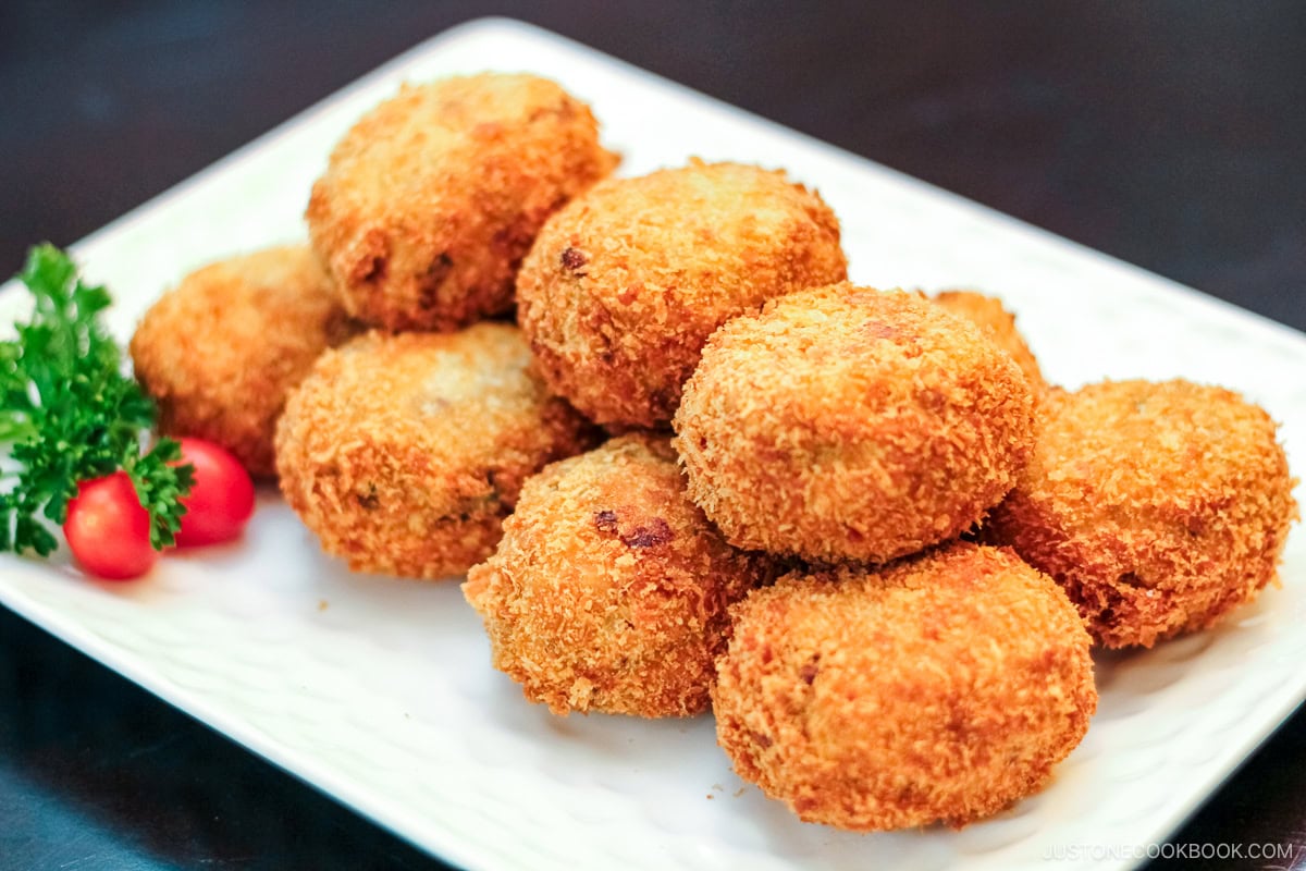 A white rectangular plate containg potato and meat croquettes.