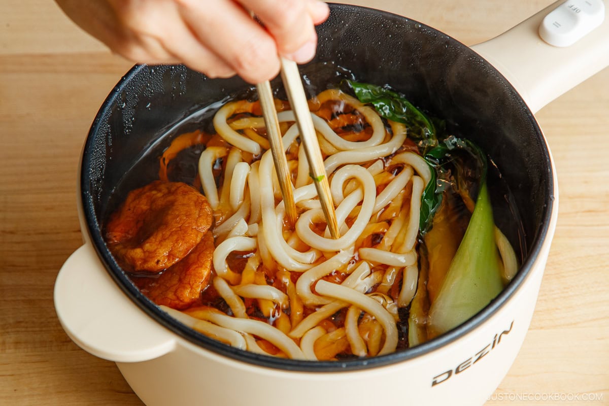 Cooking udon noodles in an electric pot.