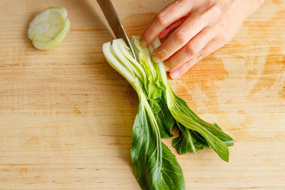 Cut bok choy in half with a knife.