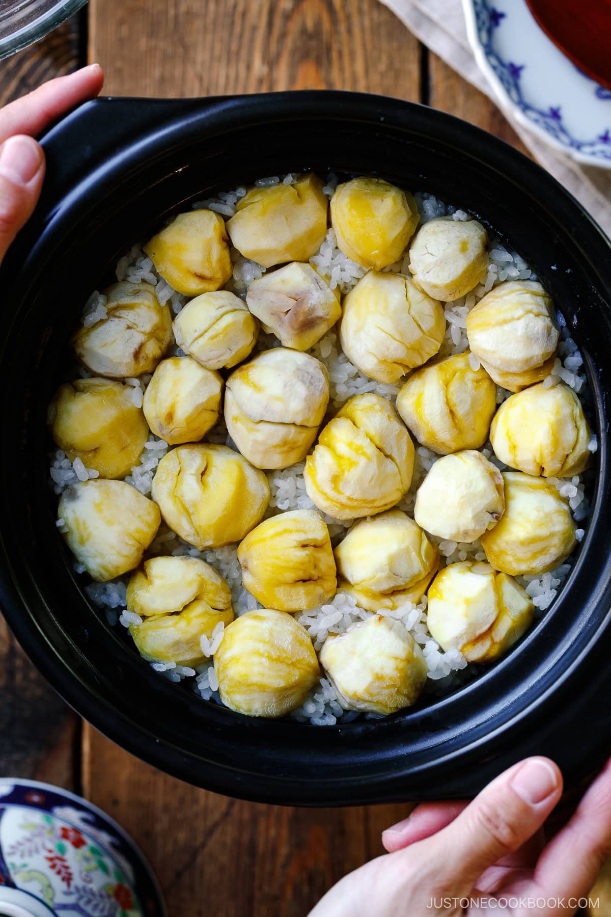 A ceramic donabe pot containing Japanese chestnut rice (kuri gohan); peeled chestnuts beautifully laying over steamed rice in a single layer.