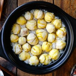 A ceramic donabe pot containing Japanese chestnut rice (kuri gohan); peeled chestnuts beautifully laying over steamed rice in a single layer.