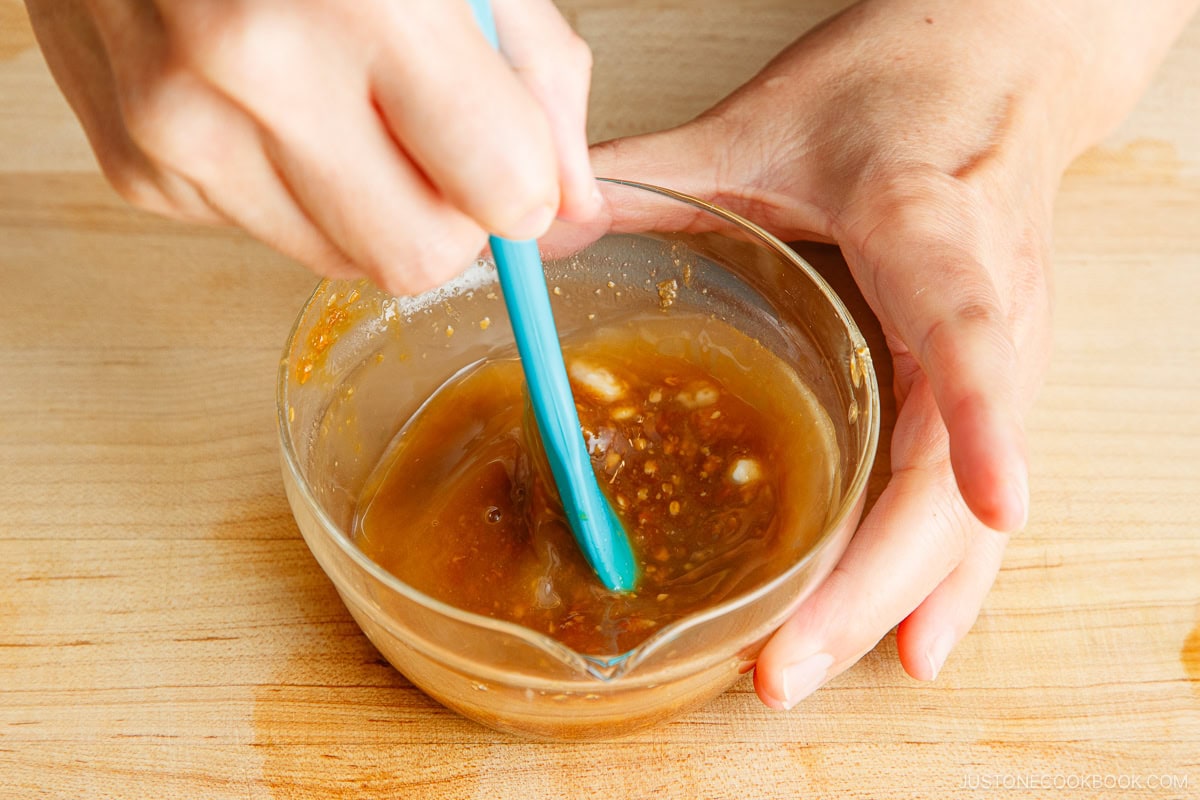 Steaming rice in a Zojirushi NEURO FUZZY rice cooker with a traditional Japanese meal in the background.