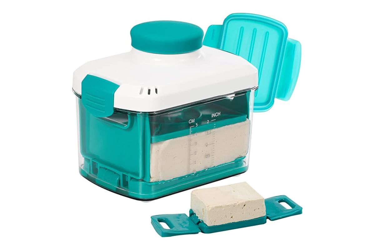 Cream cheese maker with measuring markings and a block of cream cheese on a blue mold for homemade cheese preparation.