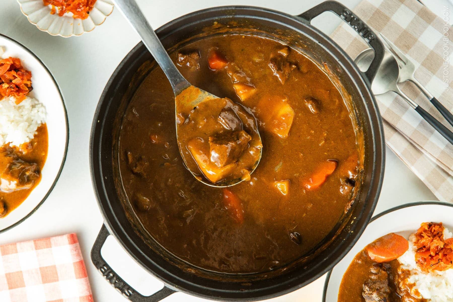 A black Staub containing Japanese beef curry, consisting of tender beef, potatoes, carrots, mushrooms, and curry roux.