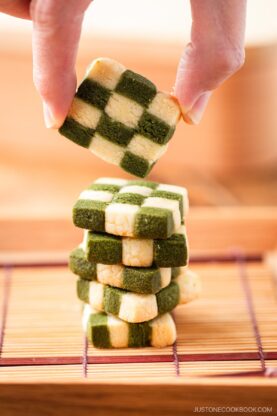 An wooden plate containing stacks of Matcha Checkerboard Cookies.