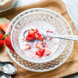 A glass bowl containing Japanese strawberry milk dessert with chunks of fresh strawberries.