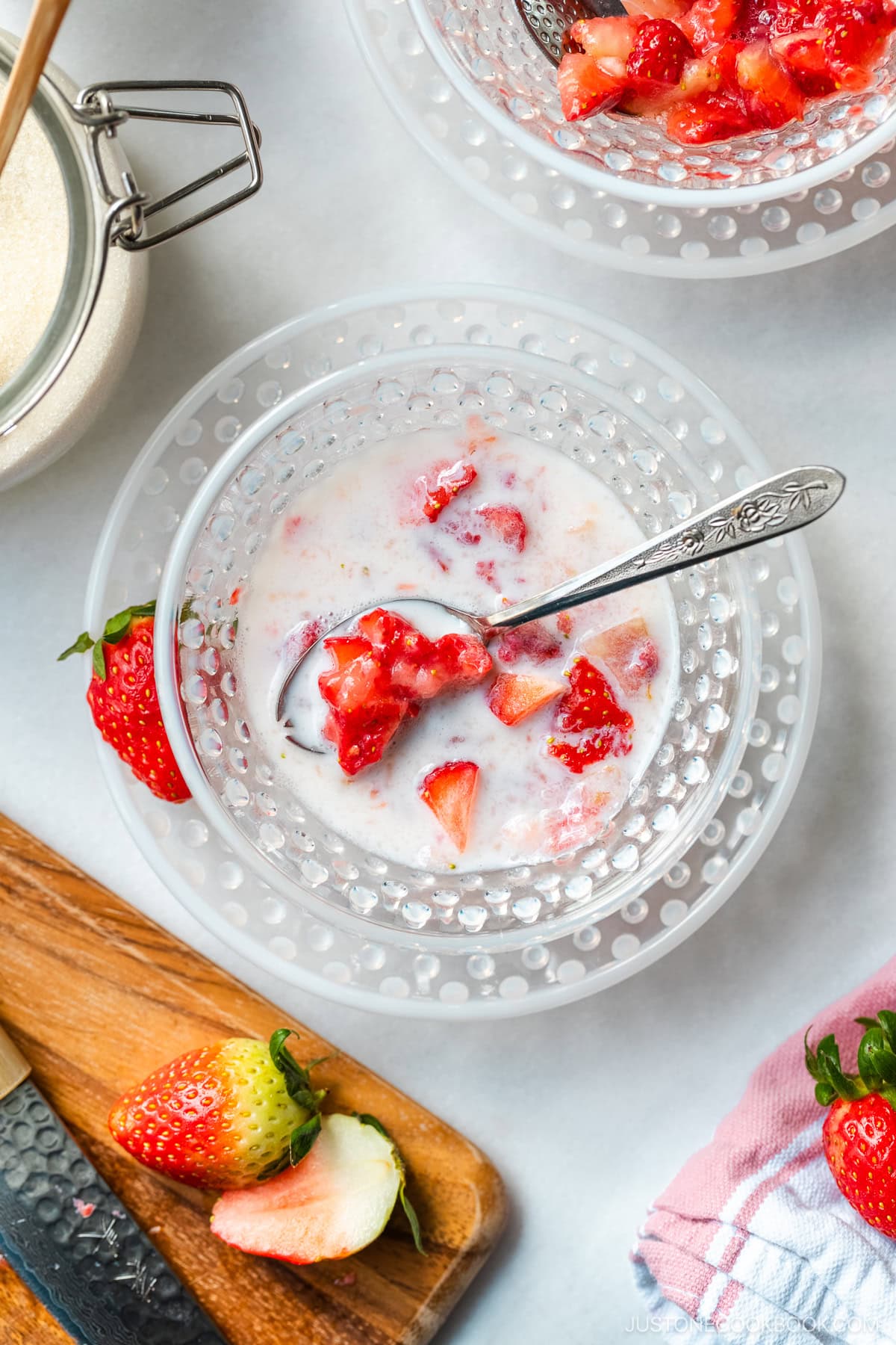 A glass bowl containing Japanese strawberry milk dessert with chunks of fresh strawberries.