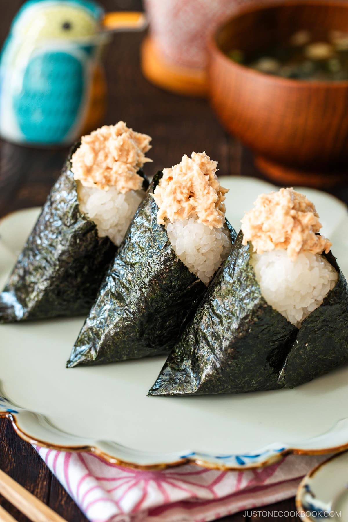 A plate containing three tuna mayo onigiri served with a wooden bowl of miso soup.