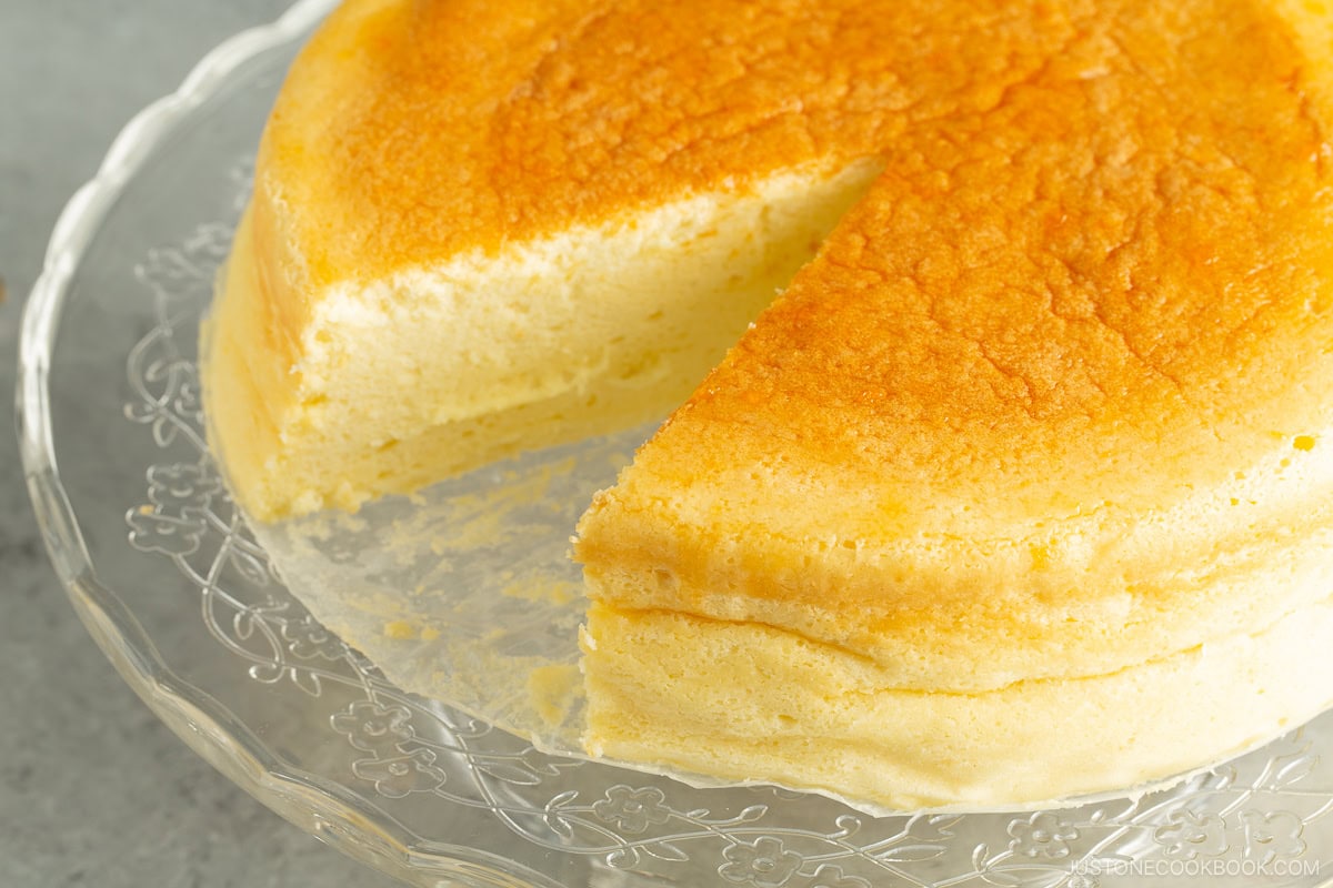 A glass cake stand containing a Japanese souffle cheesecake.