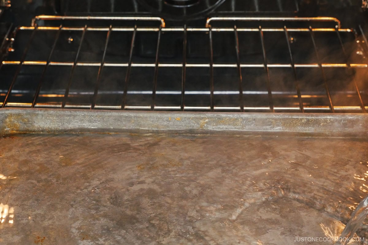 Adding hot water in the baking sheet.