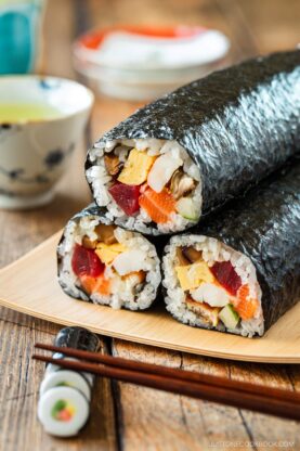 A rectangular plate containing three ehomaki, or uncut sushi rolls, prepared for setsubun festival.