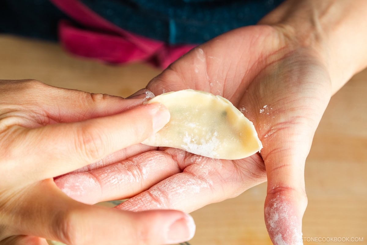 Tidying up the folded pleats of gyoza.