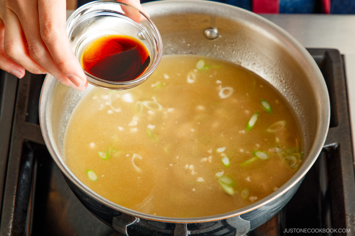 Add the soy sauce to the soup.