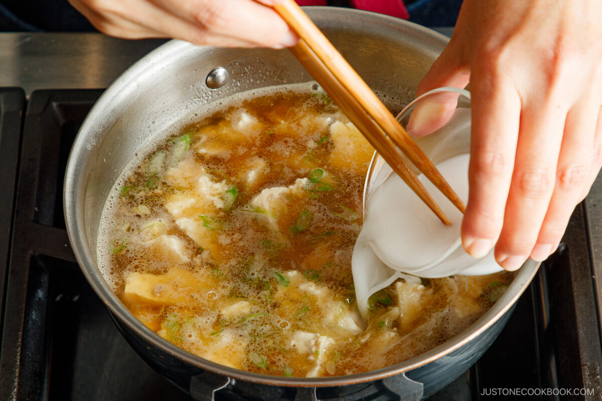 Adding cornstarch slurry to the soup.