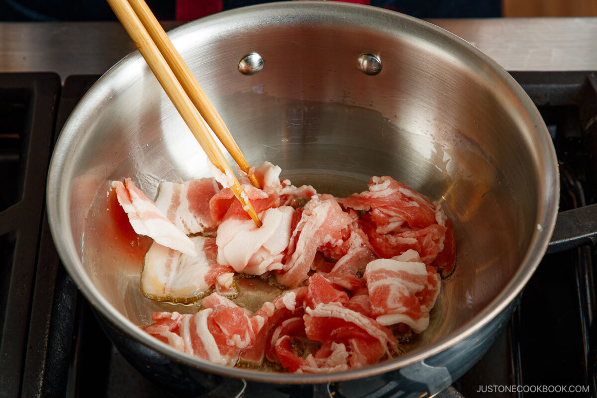 Stir frying the pork belly in the pot.