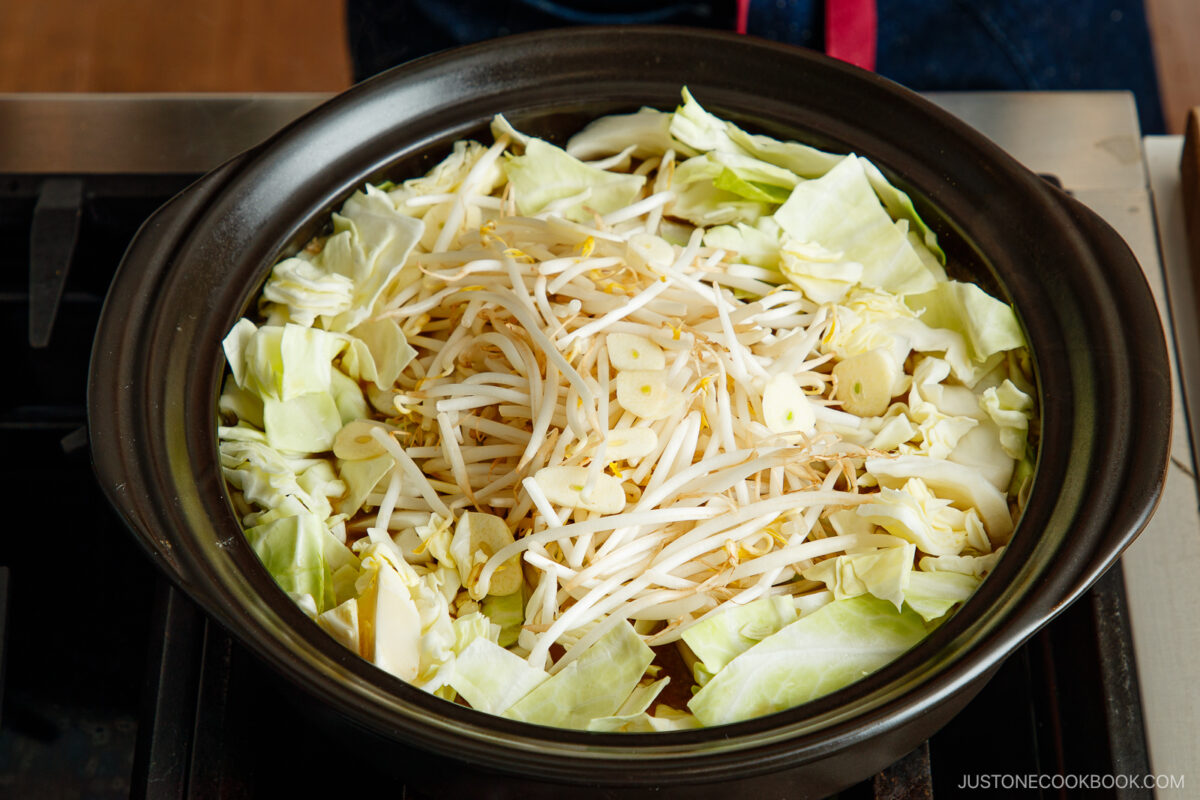 Add the cabbage and bean sproutes along with garlic slices in the soup broth.