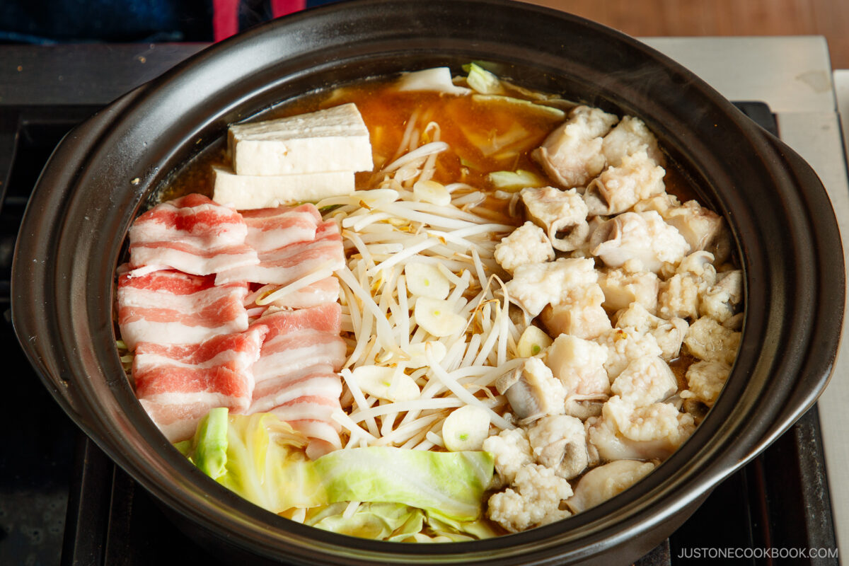 Pork belly and beef intestine on top of the cabbage and bean sprouts.