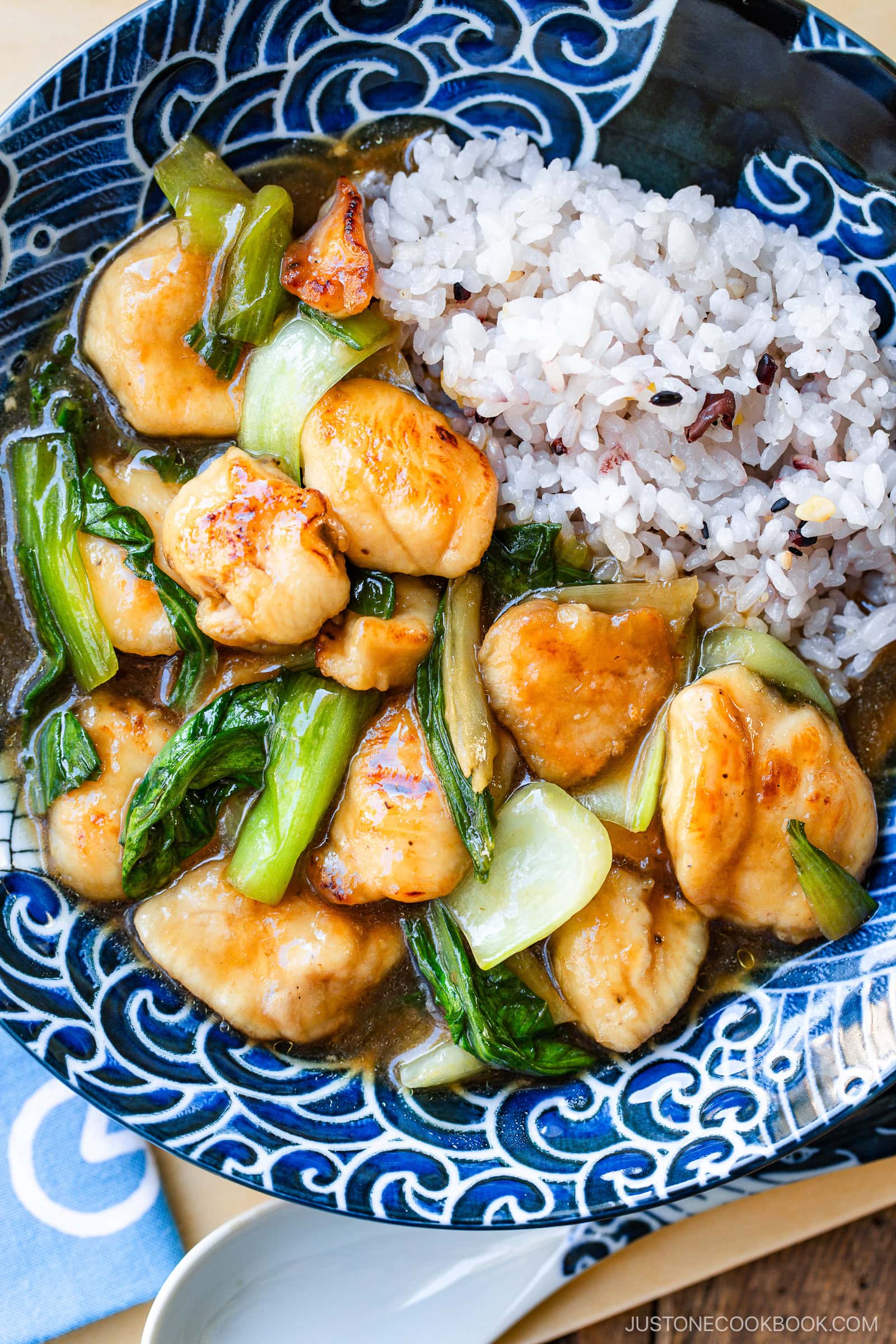 A large shallow bowl containing multi-grain rice and Chicken Bok Choy Stir Fry.