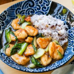 A large shallow bowl containing multi-grain rice and Chicken Bok Choy Stir Fry.