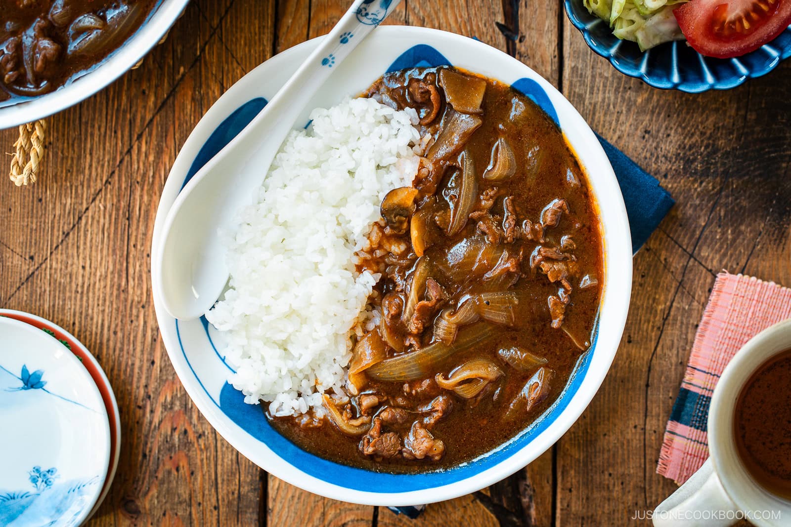 A round shallow bowl containing a bed of steamed rice and Hayashi Rice.
