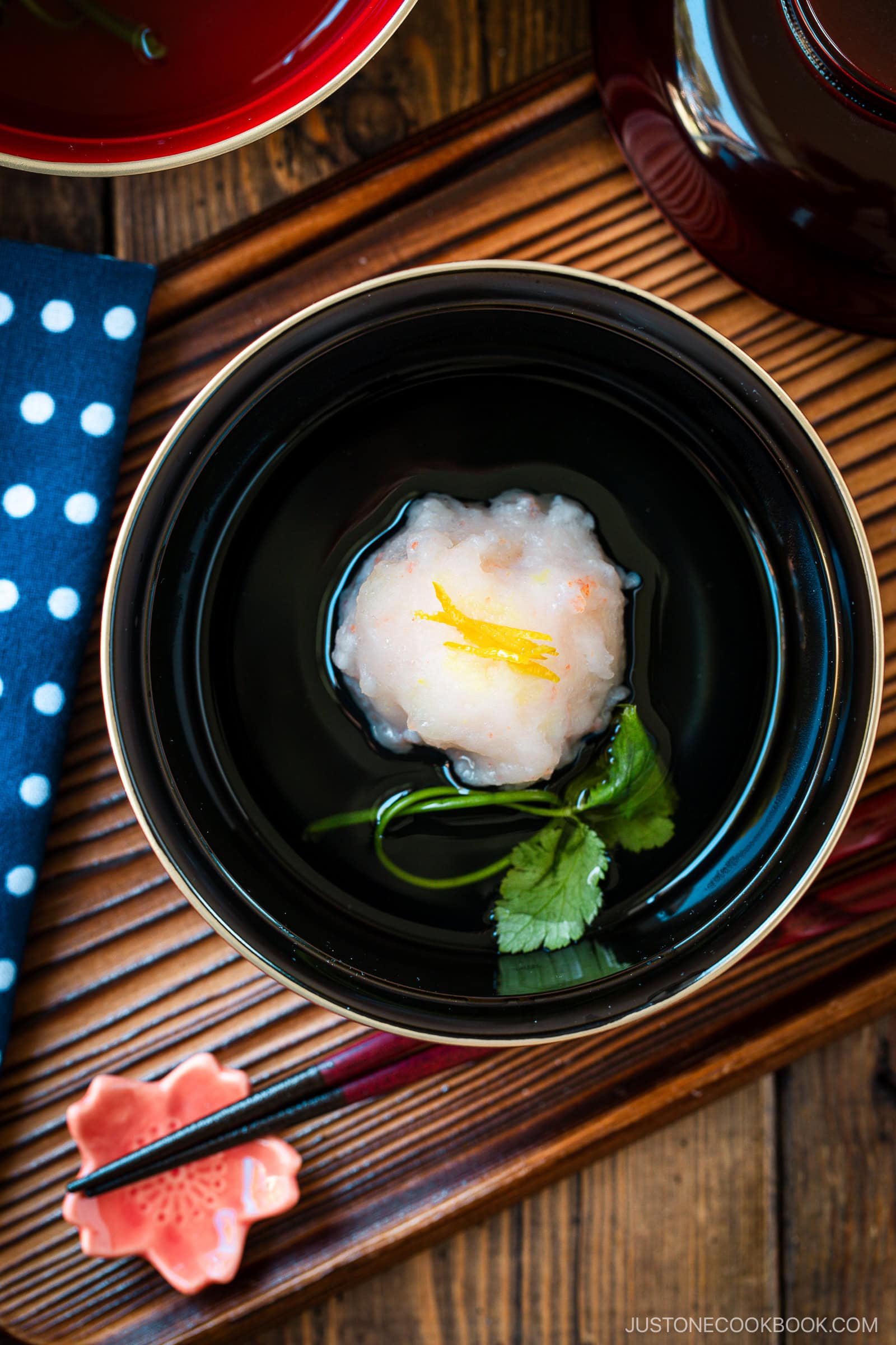 A lacquer bowl containing Ebi Shinjo, a light and fluffy shrimp dumpling, in a flavorful clear soup.