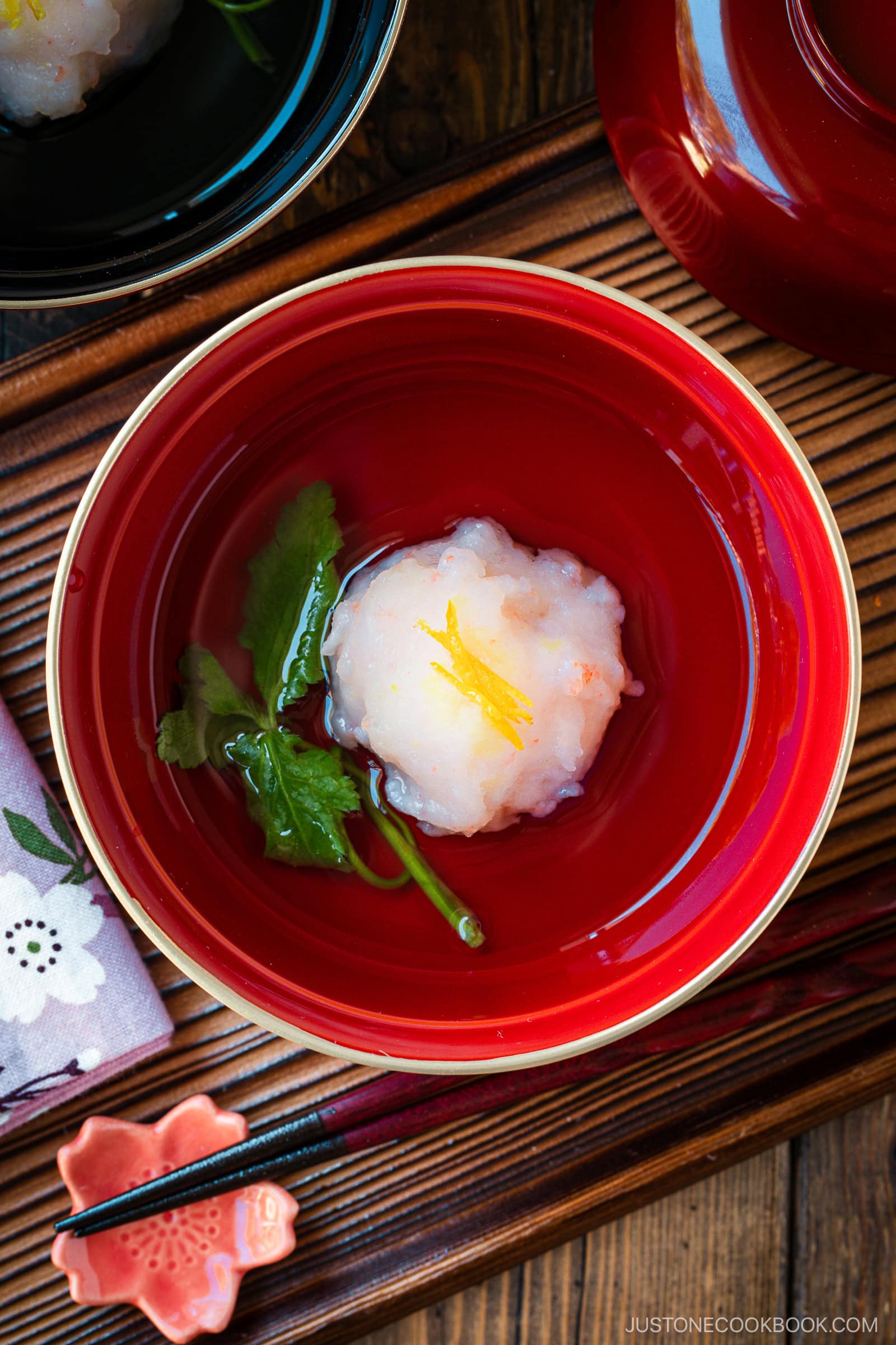 A lacquer bowl containing Ebi Shinjo, a light and fluffy shrimp dumpling, in a flavorful clear soup.
