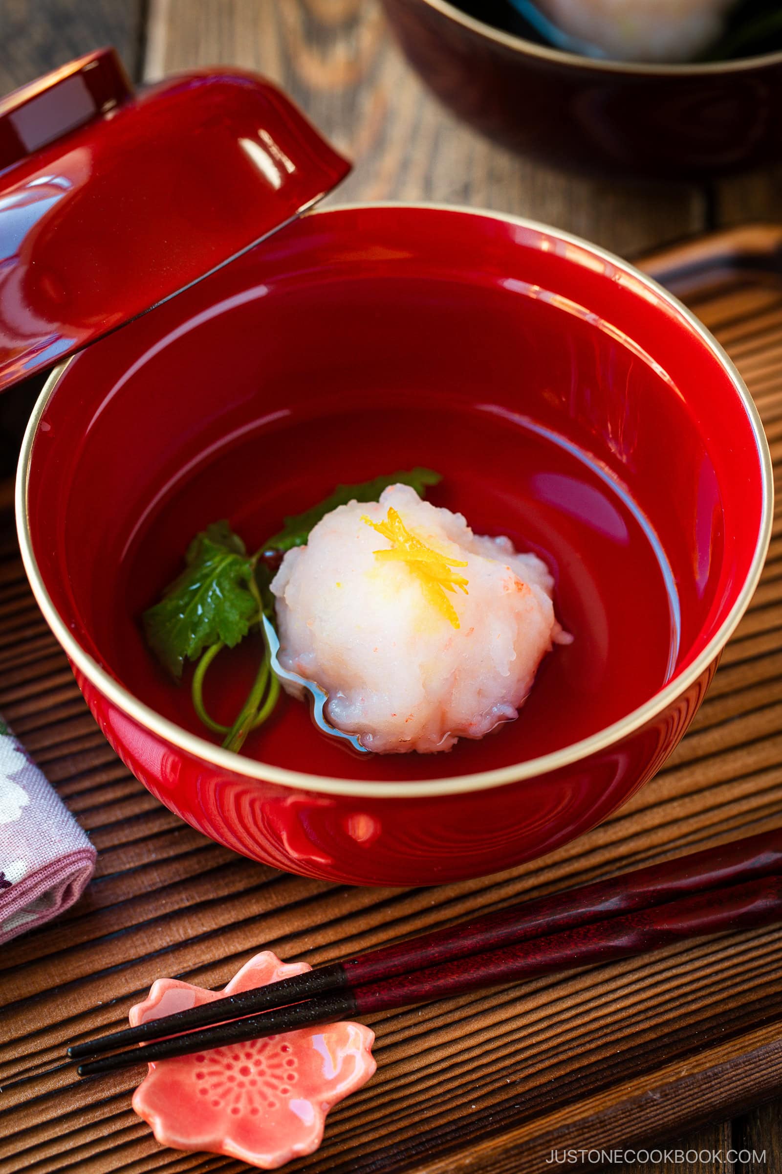 A lacquer bowl containing Ebi Shinjo, a light and fluffy shrimp dumpling, in a flavorful clear soup.