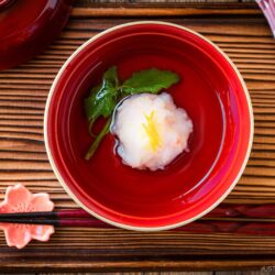 A lacquer bowl containing Ebi Shinjo, a light and fluffy shrimp dumpling, in a flavorful clear soup.