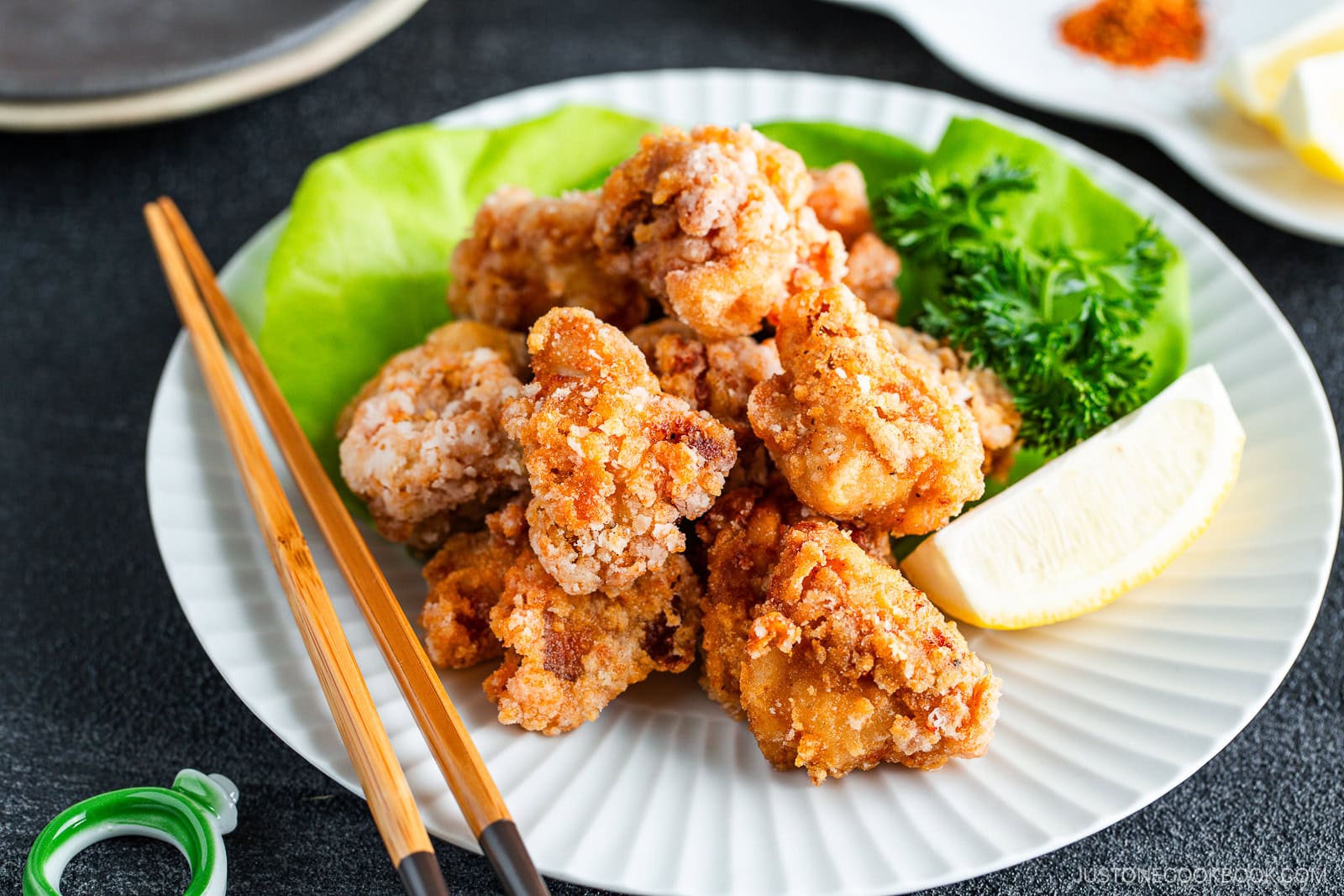 A large white plate containing gluten free karaage with a lemon wedge.