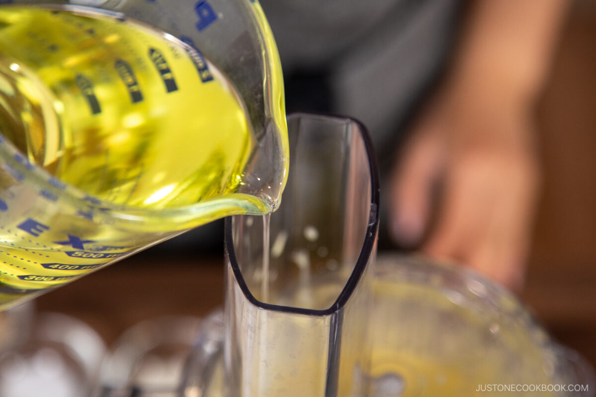 With the food processor running on the Stir setting, SLOWLY add about one-third of the neutral oil in a thin, steady stream. The mixture will begin to thicken and emulsify.