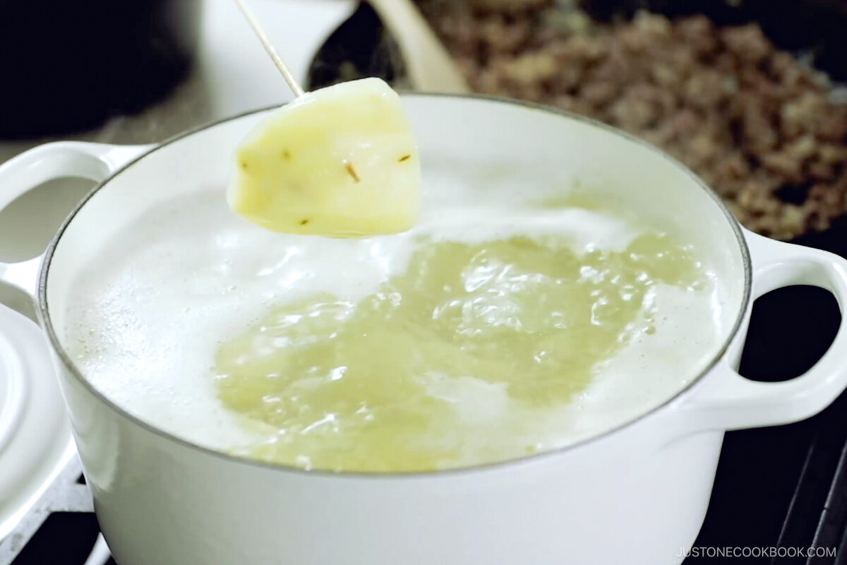 Boiling the potatoes until tender.