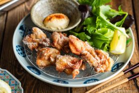 Beautiful Japanese plates containing karaage, Japanese fried chicken, garnished with lemon wedges and kewpie mayo dollop sprinkled with shichimi togarashi.