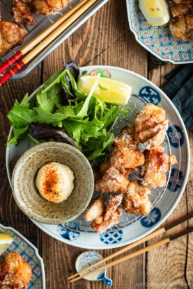 Beautiful Japanese plates containing karaage, Japanese fried chicken, garnished with lemon wedges and kewpie mayo dollop sprinkled with shichimi togarashi.
