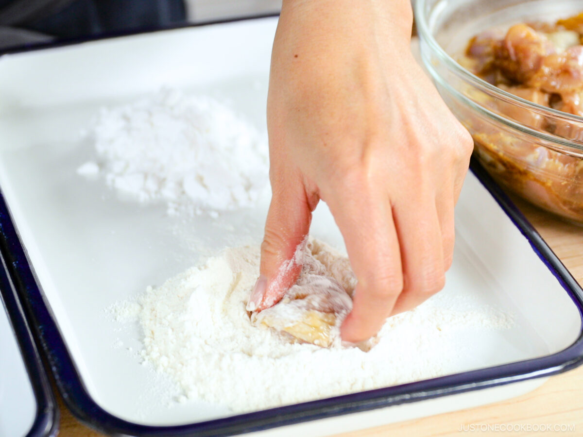 Dredging the chicken in the flour.