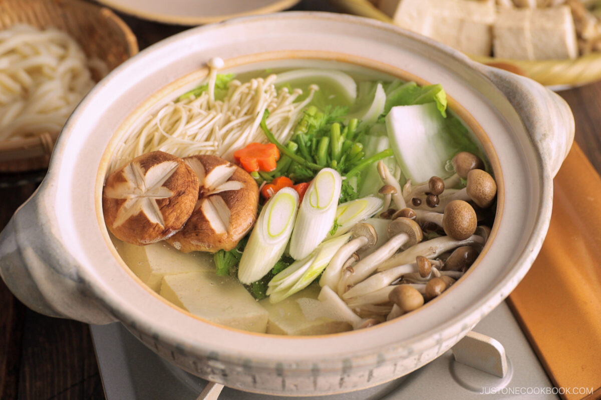 Cook vegetables, mushrooms, and tofu being cooked in a donabe, Japanese hot pot.
