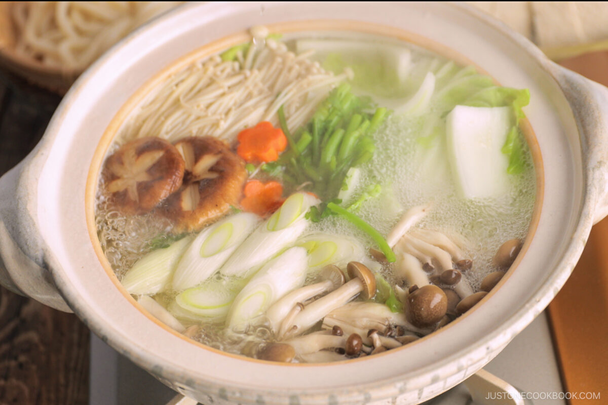 Cook vegetables, mushrooms, and tofu being cooked in a donabe, Japanese hot pot.