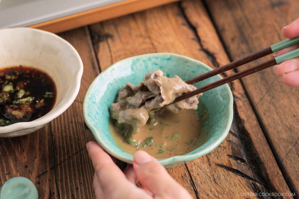 Dipping the beef in the sesame sauce.