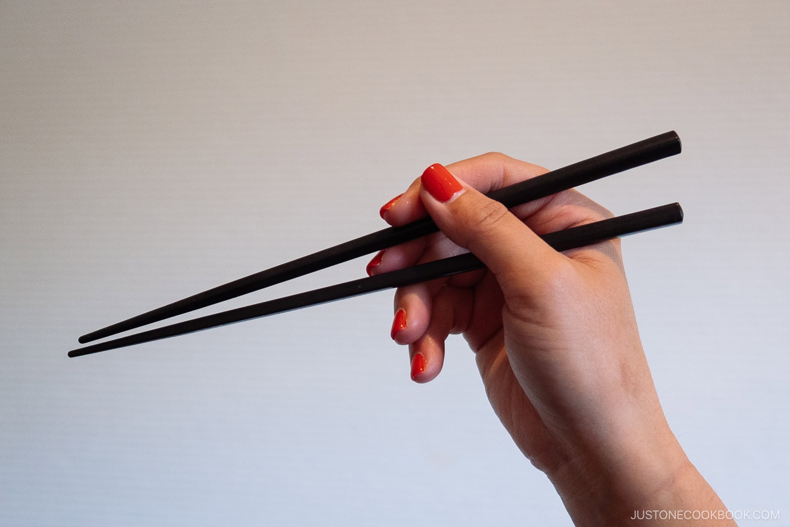Holding chopsticks with right hand.