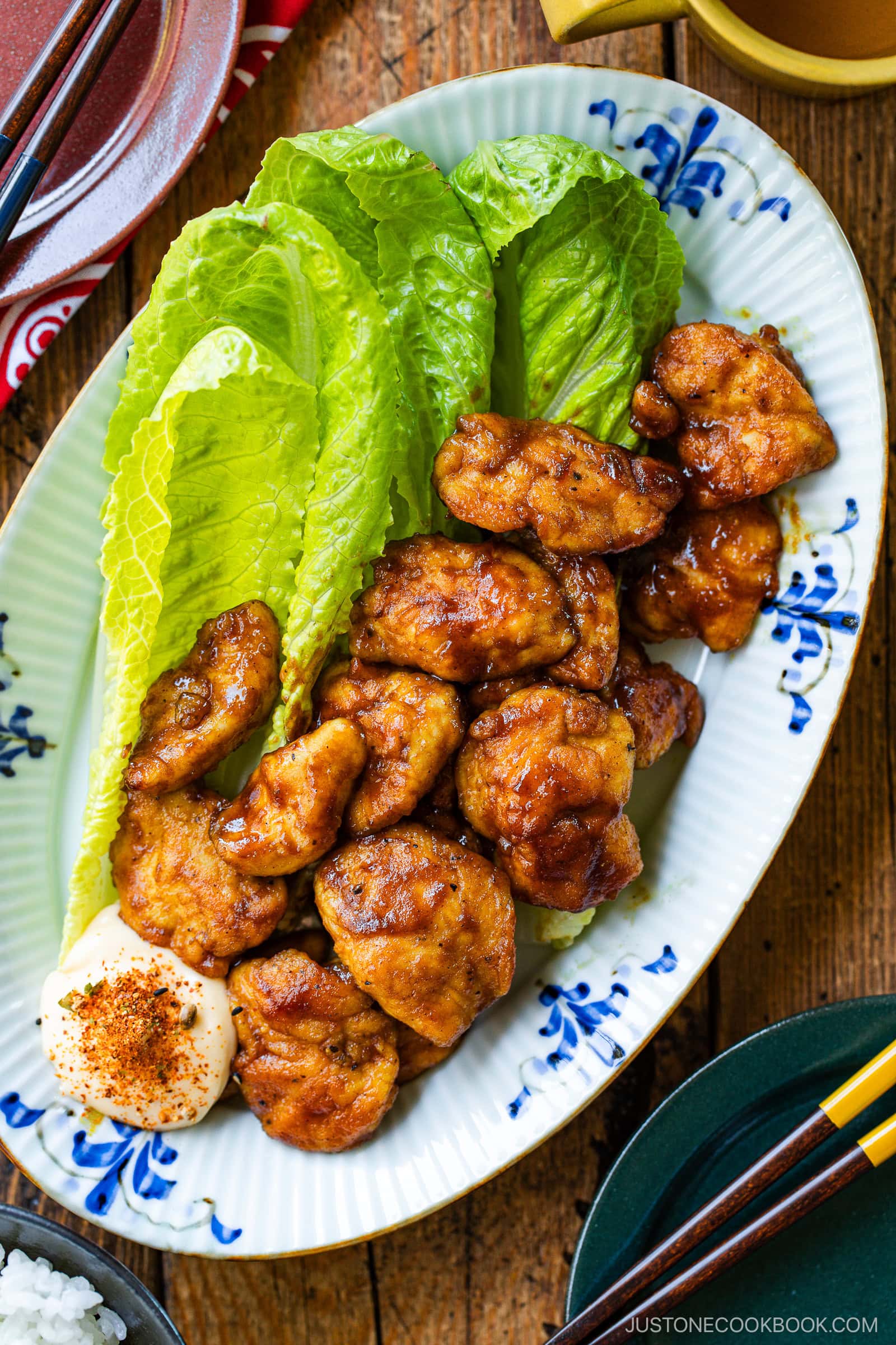 An oval shape plate containing Pan-Fried Curry Chicken garnished with lettuce.
