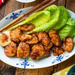 An oval shape plate containing Pan-Fried Curry Chicken garnished with lettuce.