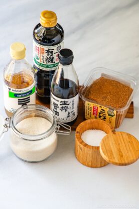 The table with Japanese seasoning staples: sugar, salt, vinegar, soy sauce, and miso.