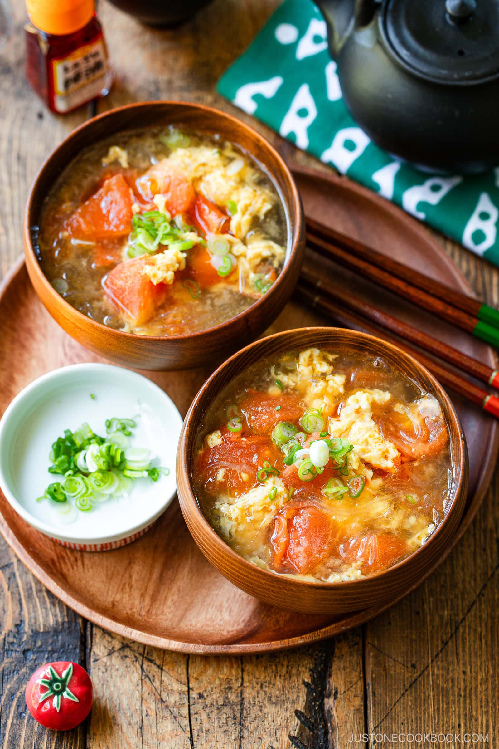 Wooden bowls containing tomato egg vermicelli soup garnished with green onion.