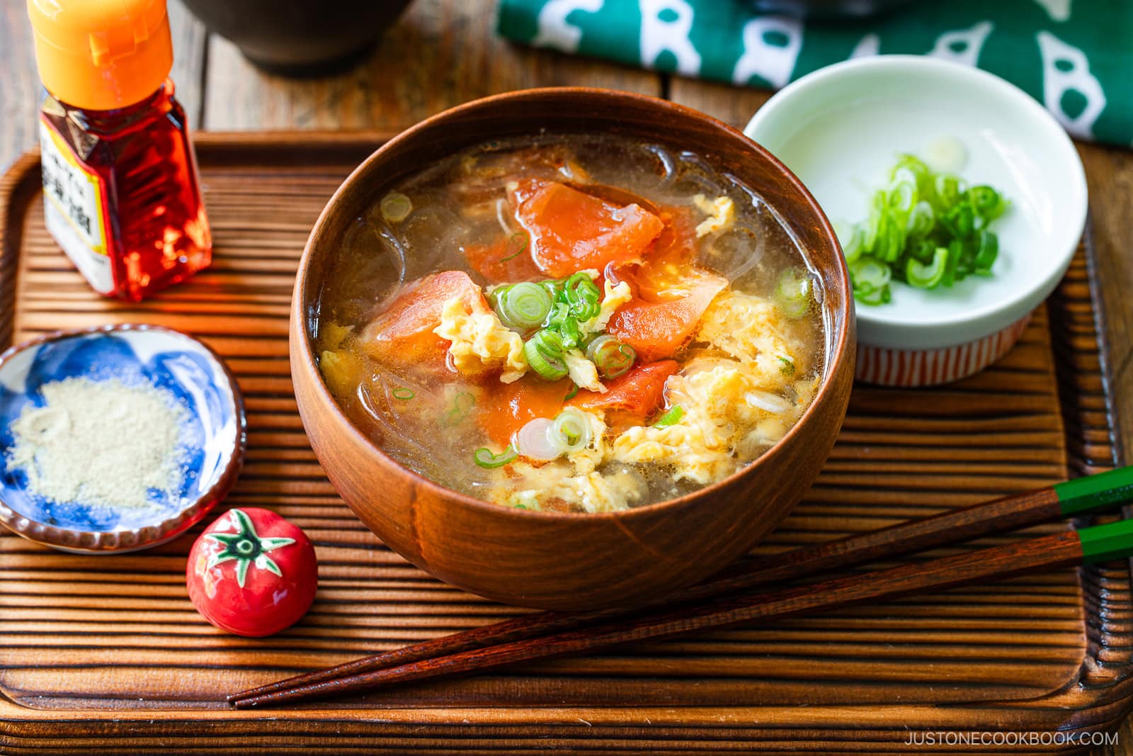 A wooden bowl containing tomato egg vermicelli soup garnished with green onion.