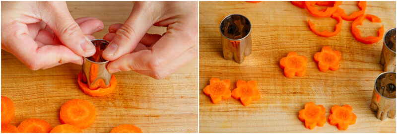 Hands pressing a metal flower-shaped cutter into a carrot slice on a wooden cutting board; to the right, several flower-shaped carrot pieces and cutters are displayed.