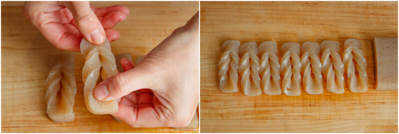 Close-up of hands twisting a piece of greyish konnyaku, and a row of six neatly twisted konnyaku pieces lined up on a wooden cutting board.