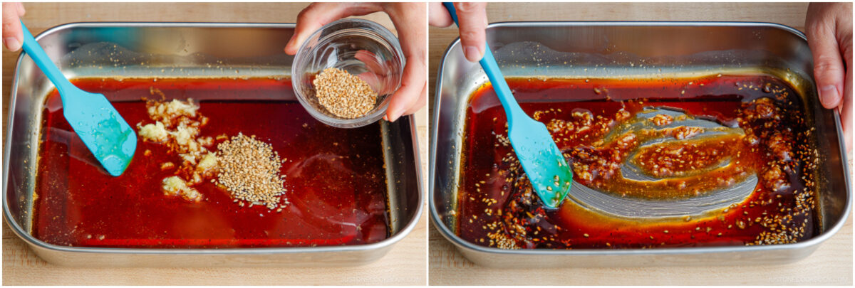 A person adds sesame seeds to a red marinade in a metal tray, then stirs the mixture with a blue spatula, blending the ingredients together.