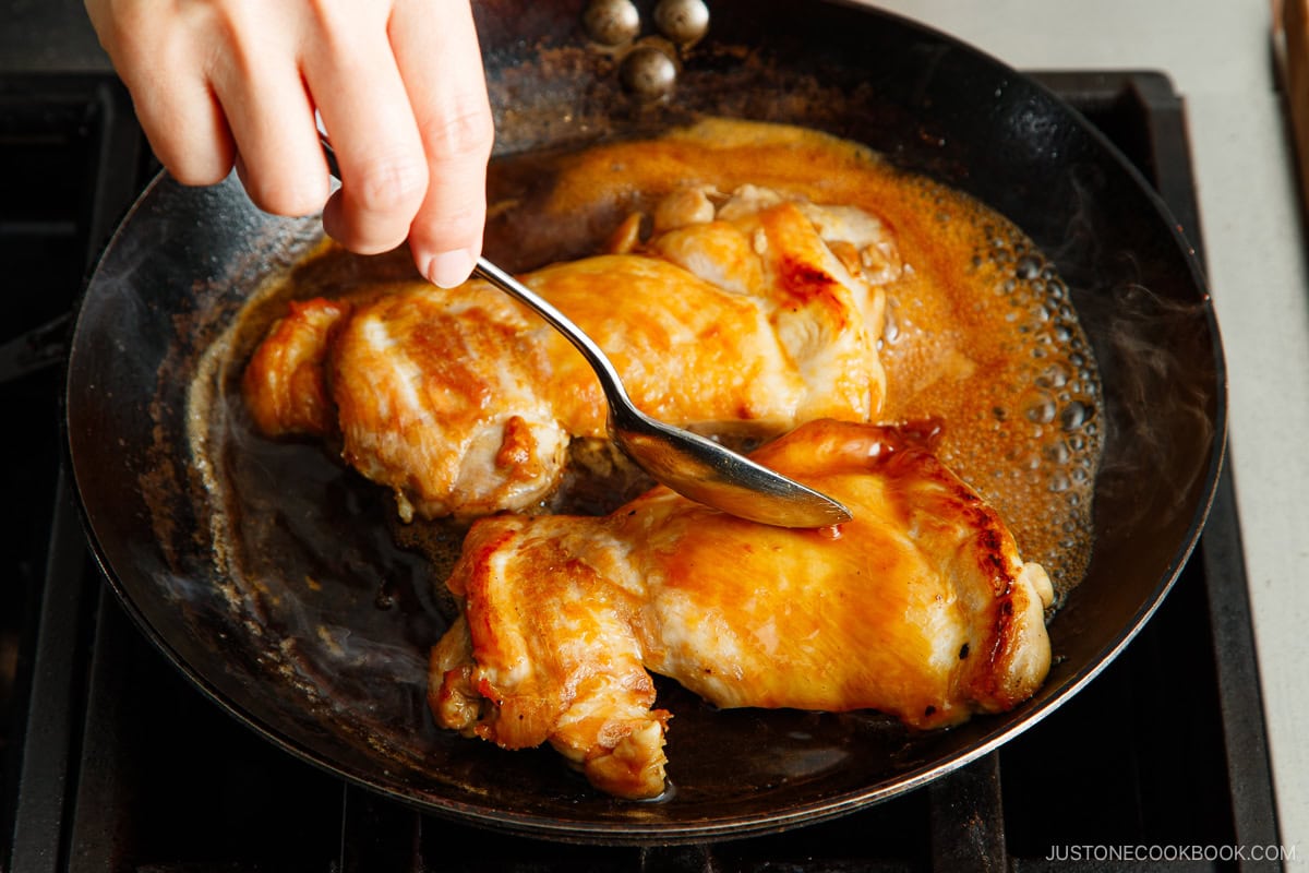 Spooning the sauce over the chicken.