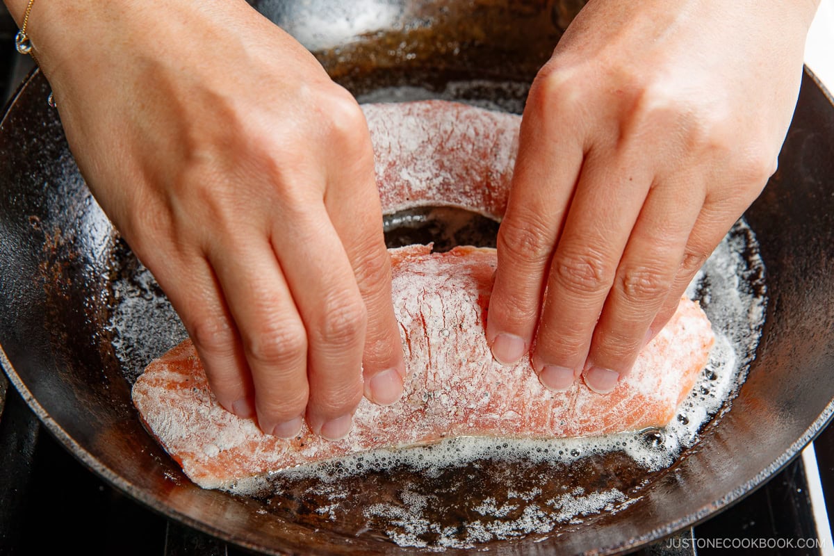 Pressing the skin of the salmon on the hot pan.